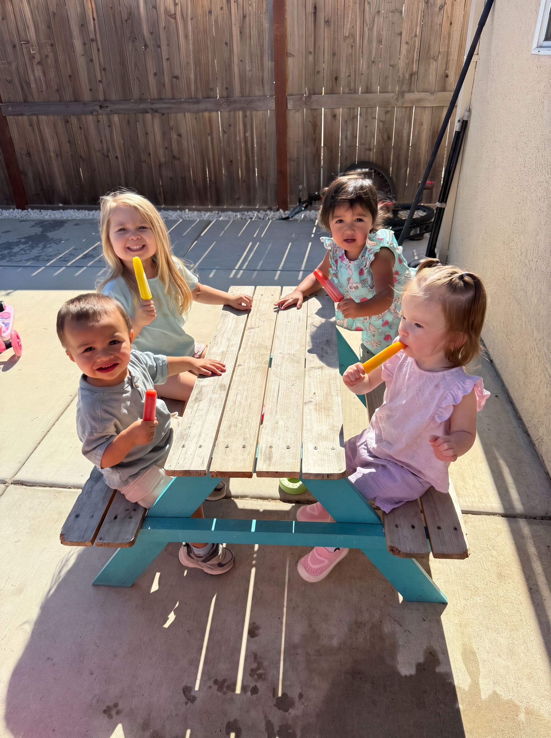 Children enjoying popsicles at the picnic table outside